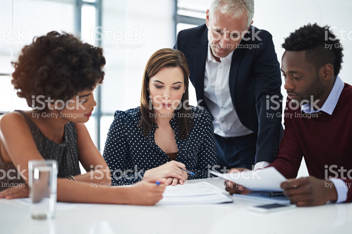 Watermarked cheesy stock photo of diverse people having a pretend business meeting.